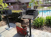 Thumbnail 27 of 37 - A barbecue grill is placed on a patio next to a pool.