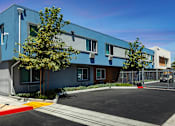Thumbnail 10 of 77 - A blue building with a parking lot in front.