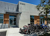 Thumbnail 6 of 77 - A building with the number 6180C on it has bicycles parked outside.