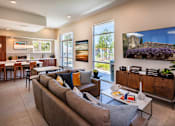Thumbnail 56 of 77 - A living room with a grey couch and a flat screen TV mounted on the wall.