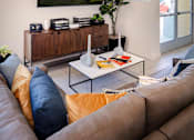 Thumbnail 47 of 77 - A living room with a brown couch and a flat screen TV mounted on the wall.