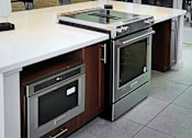 Thumbnail 55 of 77 - A modern kitchen with a white countertop and stainless steel appliances.