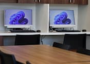 Thumbnail 44 of 77 - A conference room with a table and chairs and two monitors on the wall.