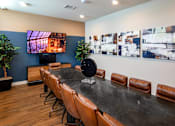 Thumbnail 33 of 77 - A conference room with a long table and chairs, a television, and a wall of paintings.
