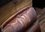 Thumbnail 36 of 77 - A brown leather couch with a wooden background.