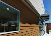 Thumbnail 16 of 77 - A modern house with a wooden exterior and a glass window.