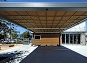 Thumbnail 42 of 77 - A building with a brown exterior and a white roof with a metal frame.