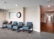Thumbnail 76 of 77 - A waiting room with four chairs and a clock on the wall.
