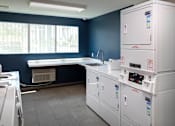 Thumbnail 64 of 77 - A row of white washing machines in a laundry room.