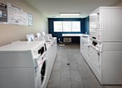 Thumbnail 65 of 77 - A laundromat with a row of washers and dryers.