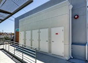 Thumbnail 68 of 77 - A small building with a red circle on the wall and a metal railing in front.