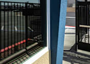 Thumbnail 19 of 21 - A view of a balcony with a black railing and a blue wall.