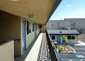 Thumbnail 6 of 21 - A long hallway with a green plant and a blue door in the distance.