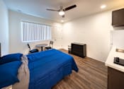 Thumbnail 5 of 21 - A bedroom with a bed covered in a blue blanket and a ceiling fan.