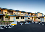 Thumbnail 14 of 21 - A parking lot in front of a building with a blue painted wheelchair symbol.
