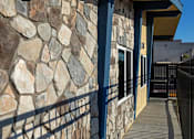 Thumbnail 20 of 21 - A stone wall with a metal railing and a wooden deck.