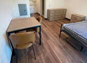 Thumbnail 11 of 15 - A room with a bed, a desk, and a chair.