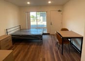 Thumbnail 9 of 15 - A bedroom with a bed, desk, and chair.