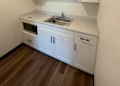 Thumbnail 13 of 15 - A kitchen with white cabinets and a wooden floor.