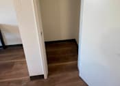Thumbnail 14 of 15 - A white door is open to a room with a wooden floor.