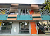 Thumbnail 1 of 15 - A building with a blue wall and a staircase leading to the second floor.