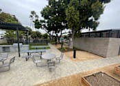 Thumbnail 8 of 15 - A patio with a table and chairs and a tree.