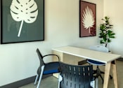 Thumbnail 26 of 37 - A white table with a black chair and a leaf picture on the wall.