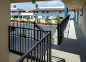 Thumbnail 27 of 37 - A balcony with a black railing and a view of a tennis court and buildings.