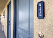 Thumbnail 20 of 37 - A blue door with a number 211 on the wall above it.