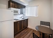 Thumbnail 13 of 37 - A kitchen with a white refrigerator, brown cabinets, and a black chair.