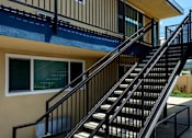 Thumbnail 12 of 37 - A staircase with a metal railing leads up to a balcony.