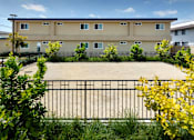Thumbnail 2 of 37 - A building with a black fence and green bushes in front.