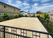Thumbnail 3 of 37 - A black fence surrounds a sandy area.