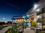 Thumbnail 109 of 116 - A building with a covered walkway and lights is shown at night.