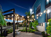 Thumbnail 100 of 116 - A patio area with a table and chairs under a lit pergola.