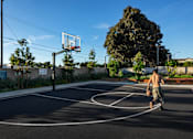 Thumbnail 104 of 116 - A man is playing basketball on an outdoor court.
