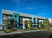 Thumbnail 91 of 116 - A modern building with a parking lot in front.