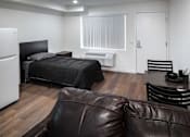 Thumbnail 84 of 116 - A black bed with a white headboard sits in a room with a brown leather couch.