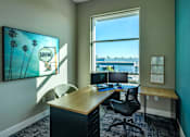 Thumbnail 62 of 116 - A room with a desk and a chair with a painting of a surfing scene on the wall.