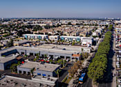 Thumbnail 59 of 116 - A large industrial building complex with a parking lot in front.