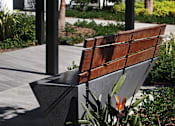 Thumbnail 42 of 116 - A wooden bench with a black metal frame is situated in a garden.