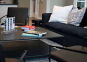 Thumbnail 36 of 116 - A black couch with a white pillow and a book on a table.
