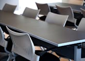 Thumbnail 34 of 116 - A white plastic chair with a black seat cushion is in front of a table.