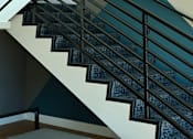 Thumbnail 21 of 116 - A staircase with a black metal railing and a concrete bench at the bottom.