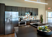 Thumbnail 22 of 116 - A modern kitchen with a stainless steel refrigerator and a plant on the counter.