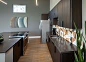 Thumbnail 23 of 116 - A modern kitchen with dark wood cabinets and a black countertop.