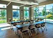 Thumbnail 30 of 116 - A conference room with a long table and chairs, and a view of the outside through large windows.