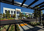 Thumbnail 7 of 116 - A modern building with a parking lot in front.