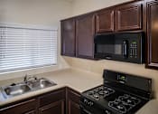 Thumbnail 26 of 36 - A kitchen with a black stove and a black microwave above it.