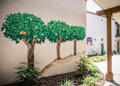 Thumbnail 7 of 36 - A mural of three trees with oranges growing on them is painted on a wall.